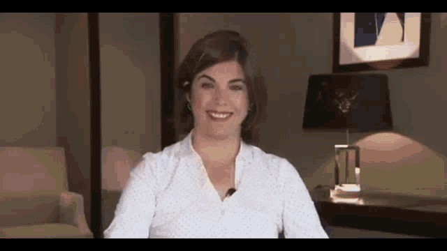 a woman in a white shirt with polka dots is smiling