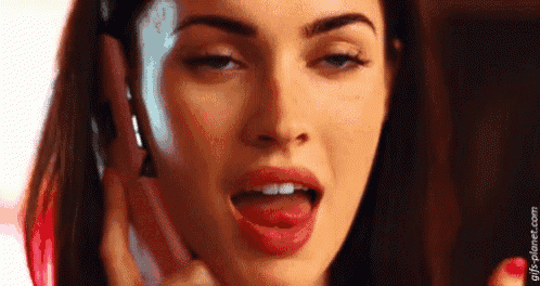 a woman is sticking her tongue out while talking on a cell phone .