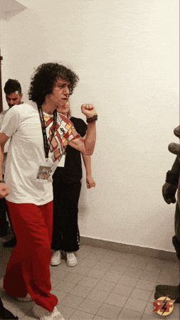 a man wearing red pants and a white shirt with a lanyard around his neck