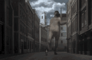 a naked man is running down a narrow street in a city .