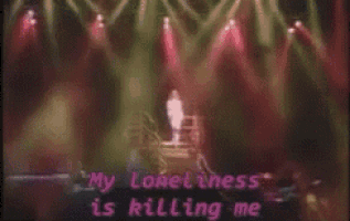 a man is standing on a stage with a microphone in front of a crowd while a song is being sung .
