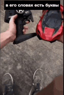 a person holding a remote control next to a red car with russian writing on the bottom