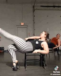 a woman is sitting on a chair with one leg up while a man sits behind her .