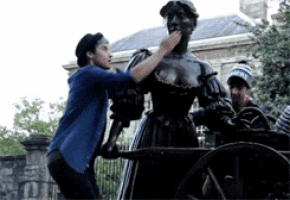a man in a blue shirt is putting his hand on a statue