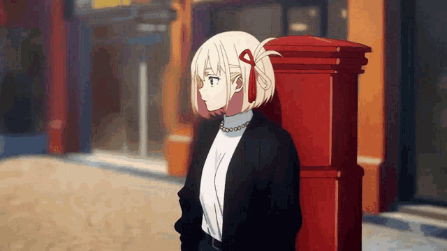 a girl leaning against a red post box on a street
