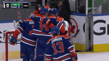 a group of hockey players celebrate a goal in front of a scoreboard