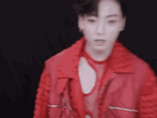 a blurry picture of a man wearing a red jacket and a red top .