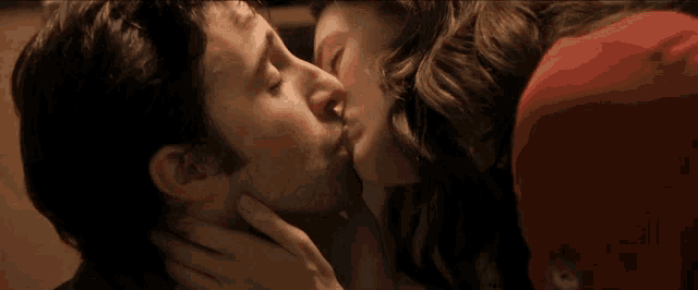 a man and a woman are kissing with a red hat on
