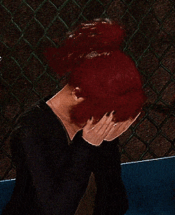a person with red hair is covering their face with their hands