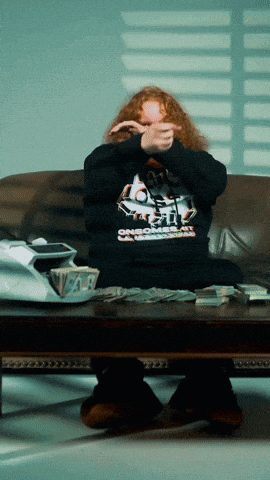 a man sitting on a couch covering his face with his hands and a sweatshirt that says one more time on it