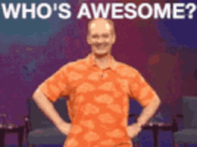 a man in an orange shirt is standing with his hands on his hips and the words who 's awesome behind him .