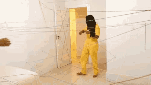 a woman in a yellow jumpsuit is surrounded by string