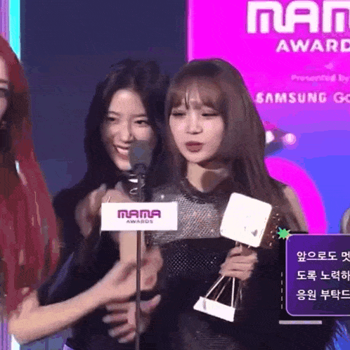 a group of women are standing in front of a microphone with a sign that says mama awards