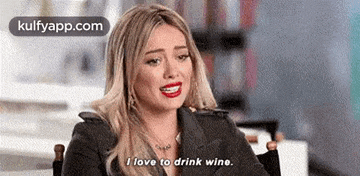 a woman is sitting in a chair and says `` i love to drink wine . ''
