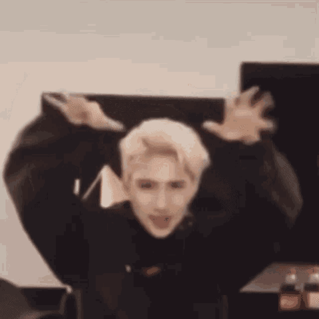 a man in a black jacket is dancing with his arms in the air .