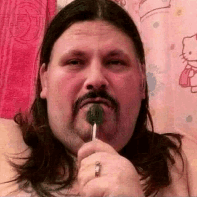 a man with a beard is holding a lollipop in his mouth .