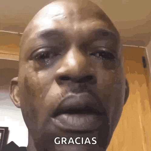 a close up of a man 's face with a tear coming out of his eye and the word gracias written on the bottom