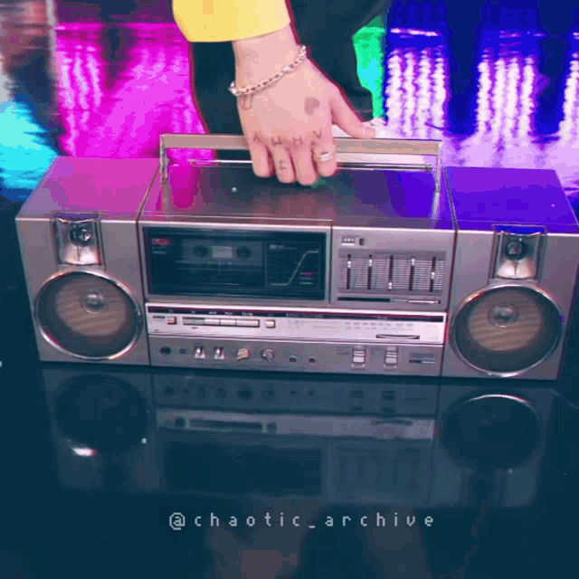 a person with a tattoo on their hand is holding a boombox with the words chaotic archive below it
