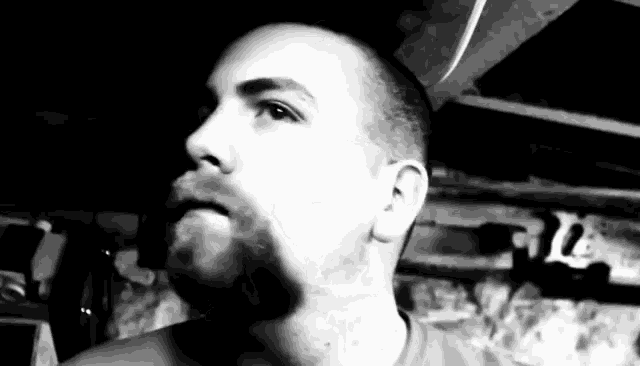 a black and white photo of a man with a beard smoking a cigarette