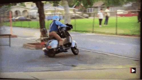 a person is riding a scooter down a street with a play button in the corner