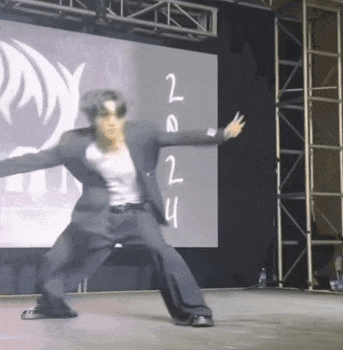 a man in a suit is dancing in front of a large screen that says 2014