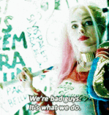 harley quinn from suicide squad is holding a sign that says we 're bad guys it 's what we do