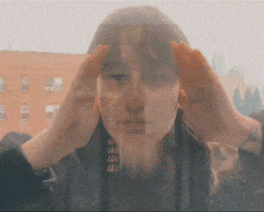 a woman 's face is visible through a window with her hands on her head