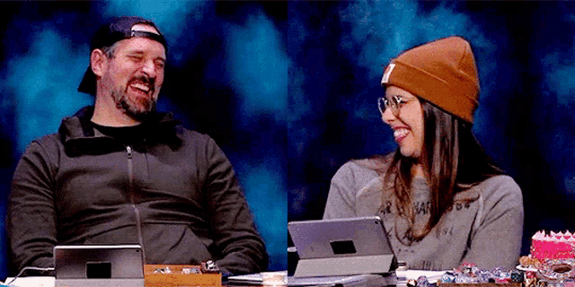 a man and a woman are sitting at a table laughing .