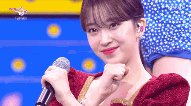 a woman in a red and gold dress is holding a microphone in her hand