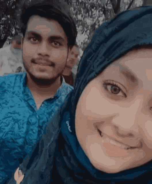 a man and a woman are posing for a picture with the man wearing a blue shirt