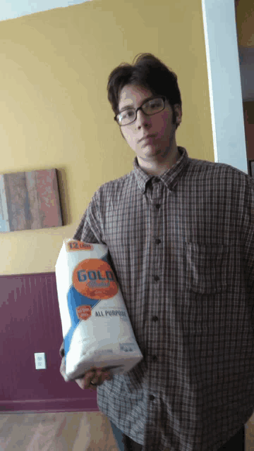 a man in a plaid shirt is holding a roll of gold all purpose toilet paper
