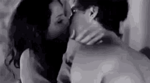 a woman is kissing a man on the neck in a black and white photo .