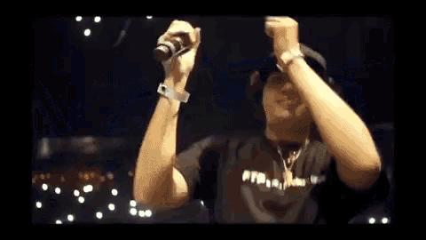 a man wearing a black shirt with the word ftp on it is raising his arms in the air .