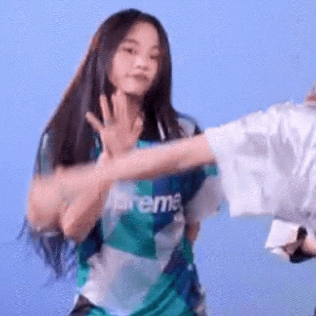 a woman wearing a supreme shirt is dancing with another woman .