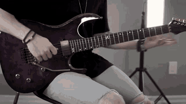a person is playing a purple electric guitar with the letter k on the neck