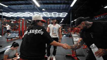a woman wearing a black shirt that says angels shakes hands with a man
