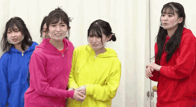 a group of young women wearing face masks are standing next to each other and shaking hands .