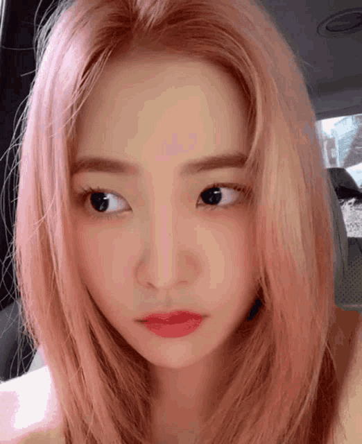 a close up of a woman 's face with pink hair and red lips