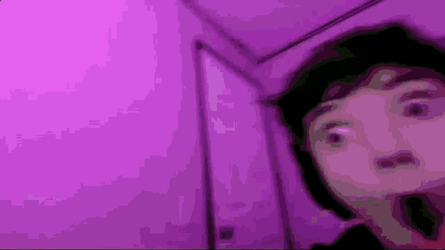 a person is standing in front of a purple wall and making a funny face .