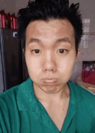 a man in a green shirt is making a funny face in front of a refrigerator