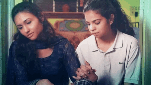 a woman wearing a white lacoste shirt is holding another woman 's hand