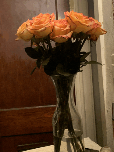 a vase filled with orange roses is on a table