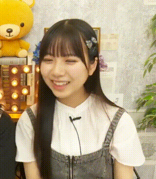 a young woman with long black hair is smiling in front of a teddy bear .