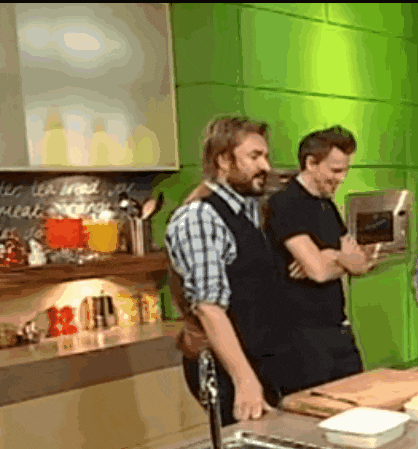 two men are standing in a kitchen with a sign on the wall that says meat storage