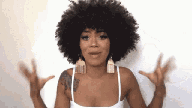 a woman with a big afro and earrings is making a funny face .