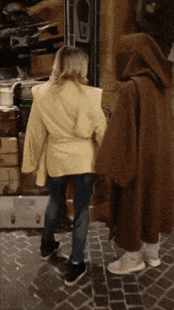 a woman in a yellow jacket is standing next to a man in a brown cape
