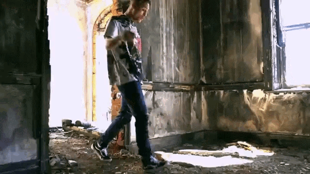 a man in a t-shirt that says ' nirvana ' on it is walking through an abandoned building