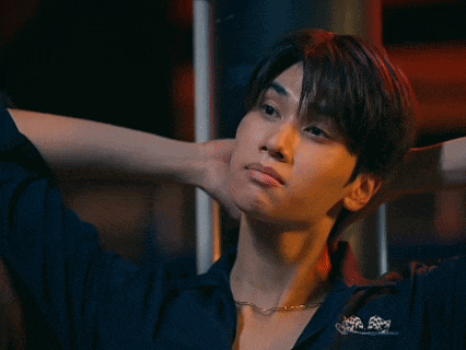 a young man with his hands behind his head is wearing a necklace and a black shirt .