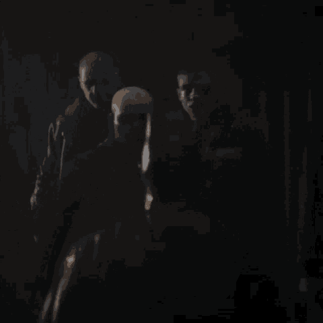 a group of men are standing in a dark room in a dark room .