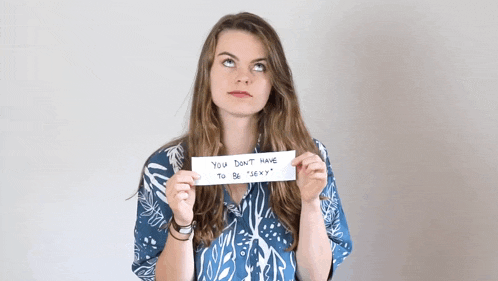 a woman holding a sign that says " you don 't have to be sexy "